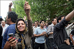Protester in Iran. Note the woman holding a cell phone in the foreground.